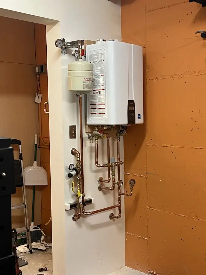 Plumbing technician inspecting water heater connections in Charlton